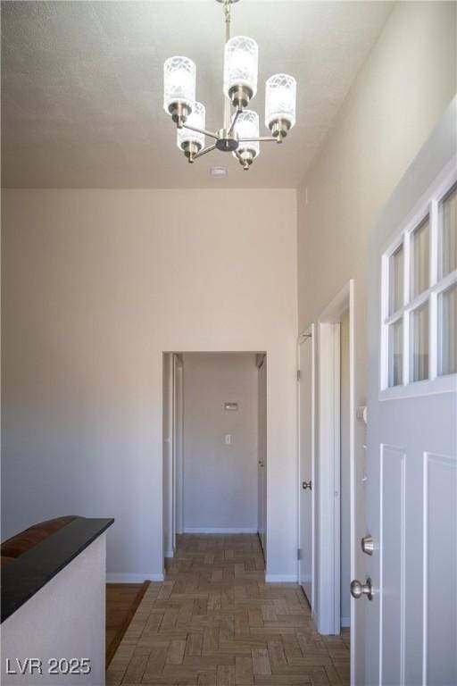 hall featuring baseboards and a chandelier