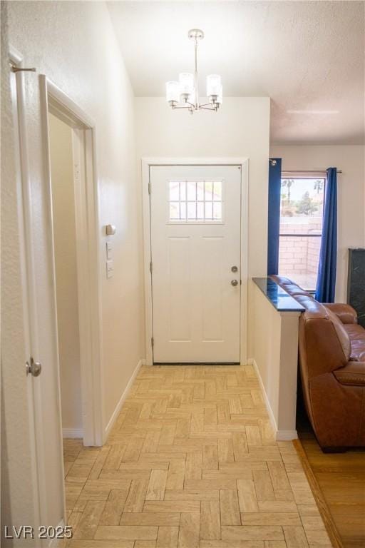 doorway to outside with an inviting chandelier, baseboards, and a wealth of natural light