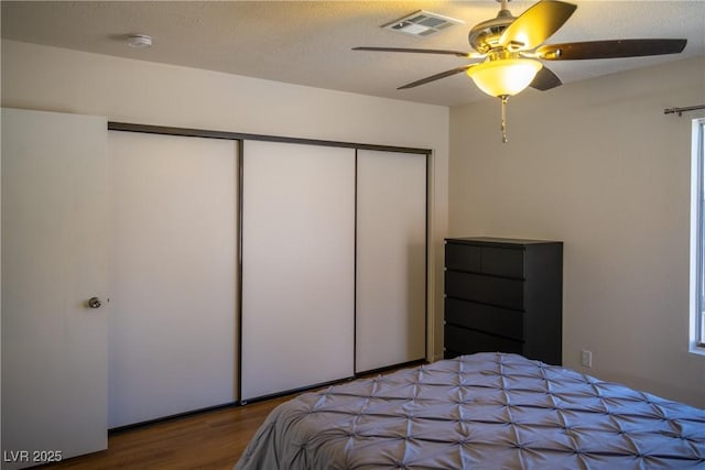 bedroom with a ceiling fan, a closet, wood finished floors, and visible vents