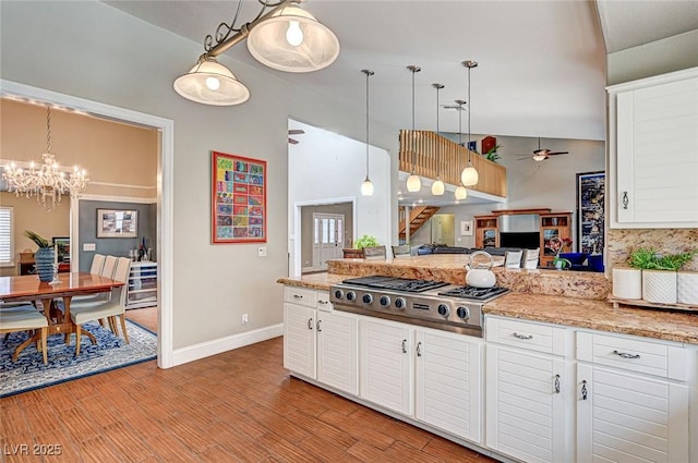 3151 Coachlight Cir, Las Vegas, NV 89117 - kitchen with pendant lighting, baseboards, white cabinets, ceiling fan with notable chandelier, and stainless steel gas stovetop