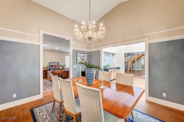 3151 Coachlight Cir, Las Vegas, NV 89117 - dining room with a notable chandelier, high vaulted ceiling, stairs, baseboards, and wood finished floors
