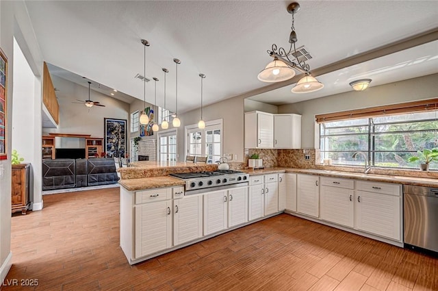 3151 Coachlight Cir, Las Vegas, NV 89117 - kitchen featuring a fireplace, a sink, white cabinets, a peninsula, and stainless steel appliances