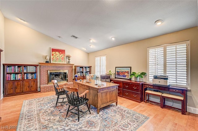 3151 Coachlight Cir, Las Vegas, NV 89117 - office space with visible vents, light wood-style floors, a brick fireplace, and vaulted ceiling