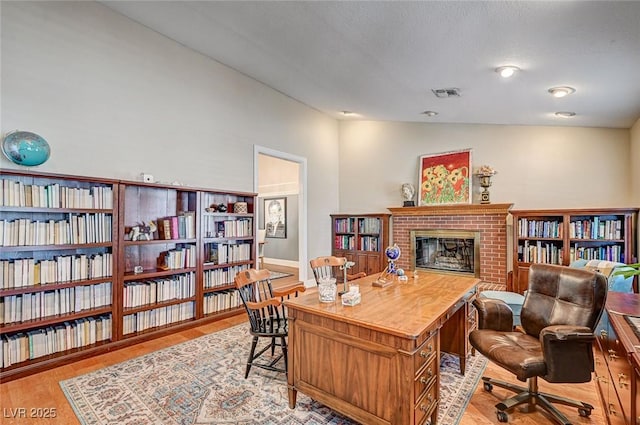 3151 Coachlight Cir, Las Vegas, NV 89117 - office area with baseboards, a brick fireplace, light wood finished floors, and visible vents