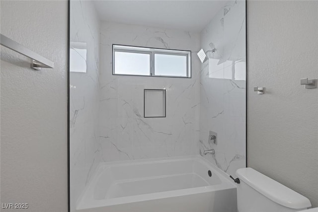 full bath with a textured wall, toilet, and tub / shower combination