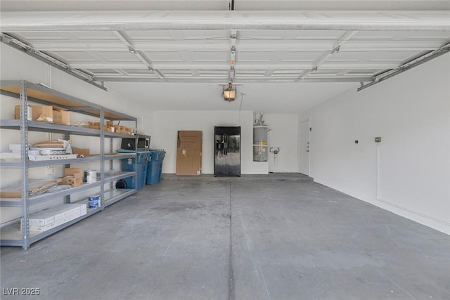 garage featuring strapped water heater, black fridge, and a garage door opener