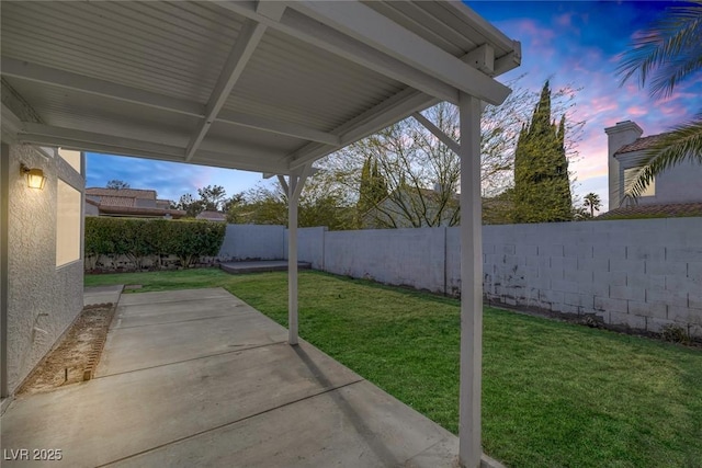 patio terrace at dusk with a lawn and a fenced backyard