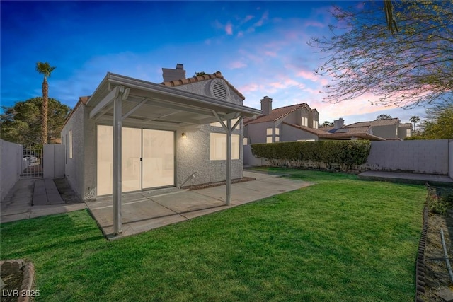 rear view of property featuring a chimney, a fenced backyard, a patio area, and stucco siding