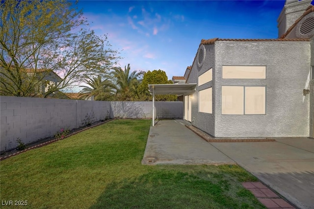 yard at dusk with a fenced backyard and a patio