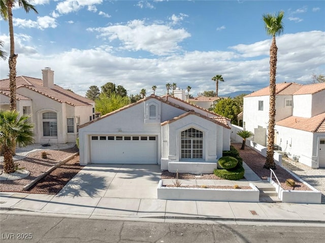 mediterranean / spanish-style home featuring concrete driveway, an attached garage, a tile roof, and stucco siding