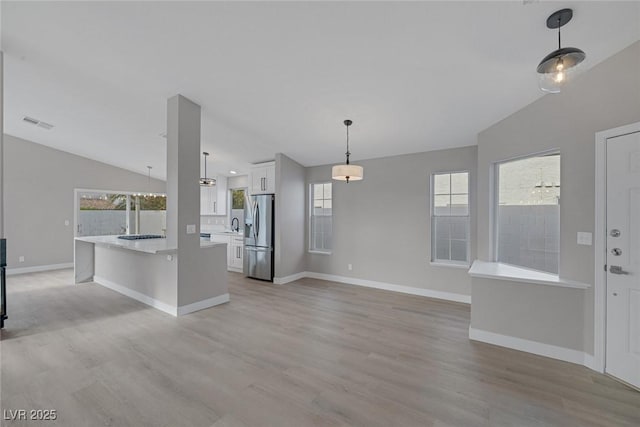 kitchen featuring light countertops, white cabinetry, vaulted ceiling, and stainless steel fridge with ice dispenser