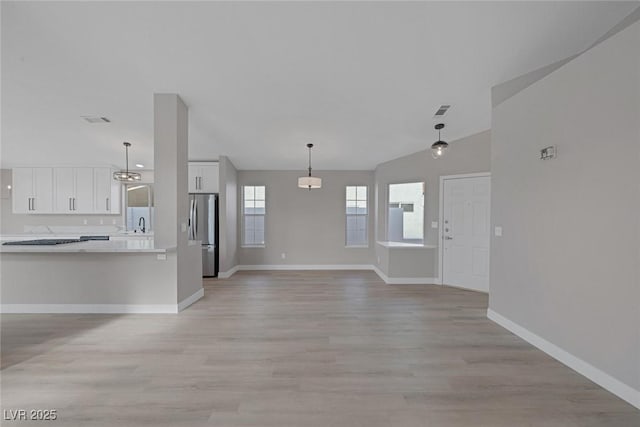 interior space with white cabinets, light wood-style floors, light countertops, freestanding refrigerator, and visible vents