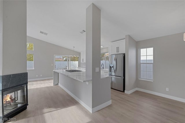 kitchen with baseboards, white cabinetry, stainless steel fridge with ice dispenser, light wood-style flooring, and vaulted ceiling