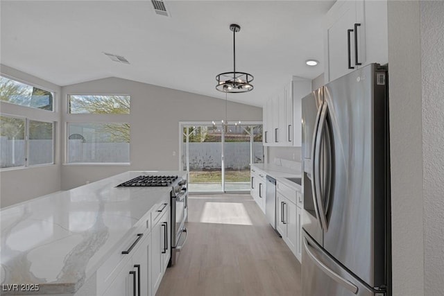 kitchen featuring light stone countertops, a notable chandelier, light wood finished floors, stainless steel appliances, and visible vents