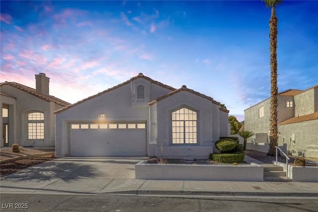 view of front facade featuring an attached garage, stucco siding, a tile roof, and concrete driveway