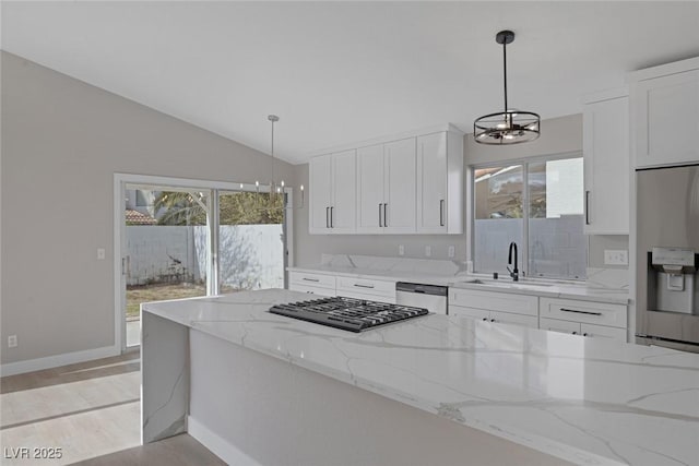 kitchen with appliances with stainless steel finishes, a sink, a chandelier, white cabinetry, and vaulted ceiling