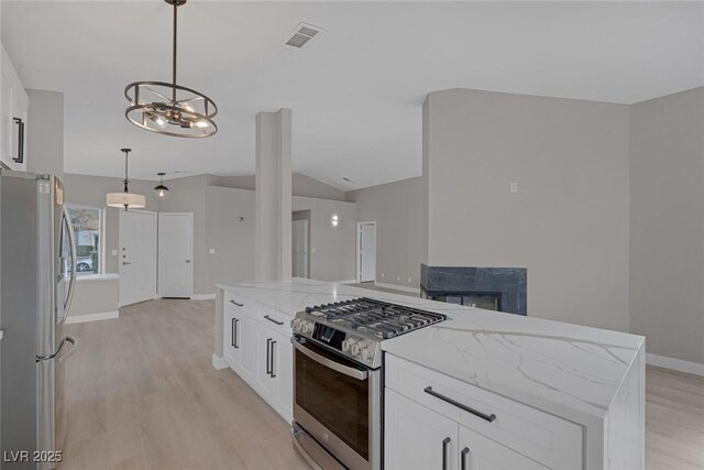 kitchen with light stone counters, light wood-style flooring, appliances with stainless steel finishes, and white cabinets
