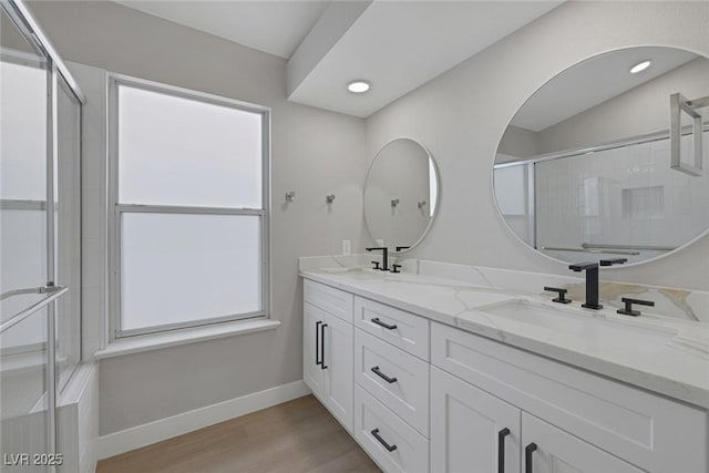 bathroom with baseboards, a sink, wood finished floors, and a shower stall