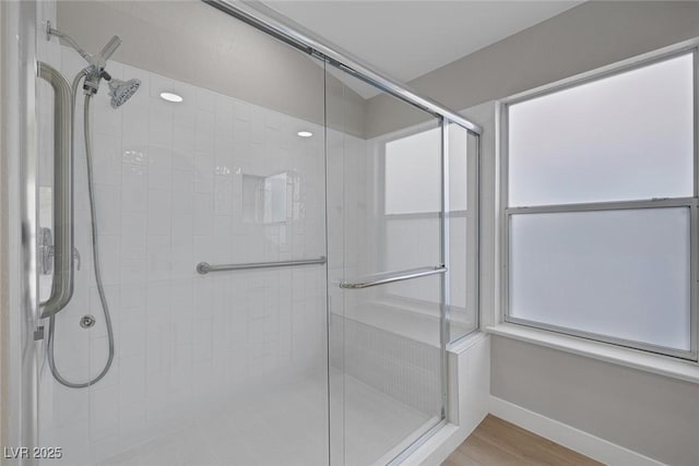 bathroom featuring baseboards, wood finished floors, and a stall shower