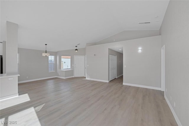unfurnished living room featuring baseboards, vaulted ceiling, light wood-type flooring, and visible vents