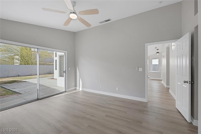 spare room with baseboards, a ceiling fan, wood finished floors, and visible vents