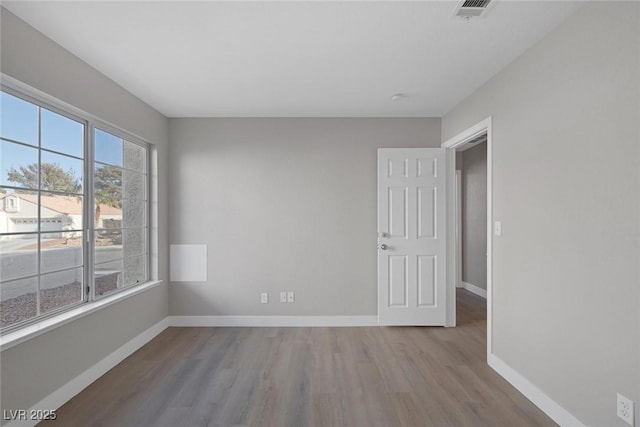 unfurnished room featuring baseboards, wood finished floors, and visible vents