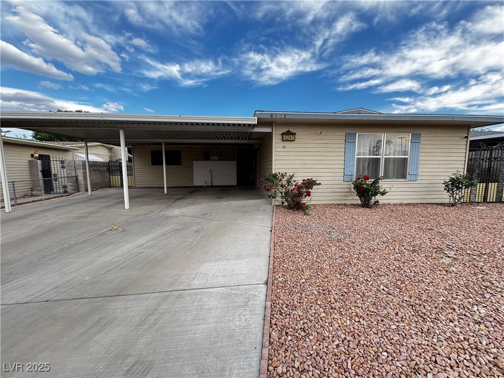 ranch-style house with driveway, an attached carport, and fence