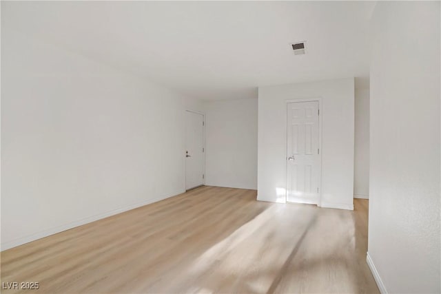 spare room with visible vents, light wood-style flooring, and baseboards