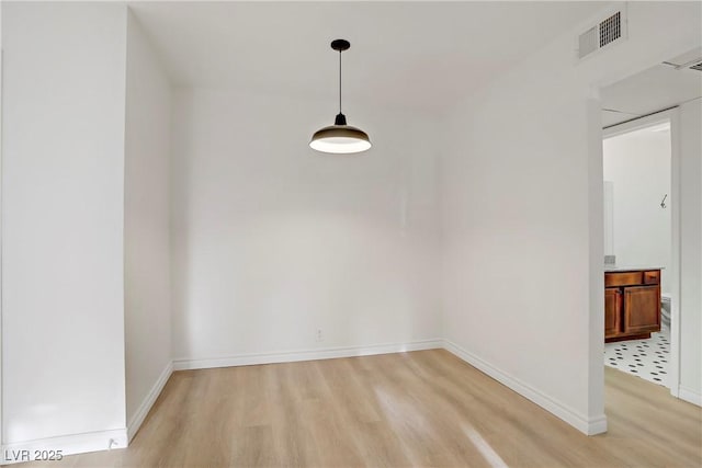 unfurnished dining area with baseboards, light wood-type flooring, and visible vents