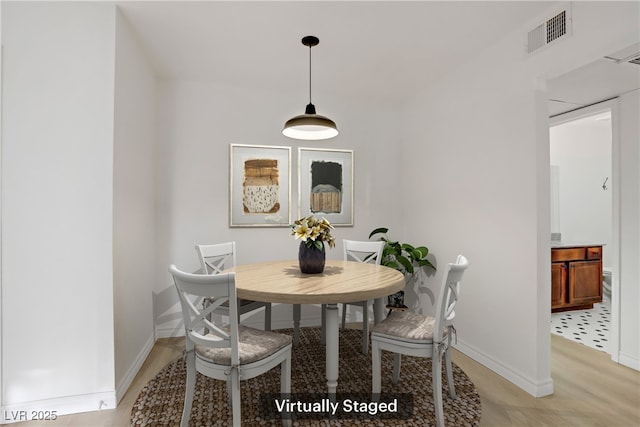 dining area with visible vents, light wood-style floors, and baseboards
