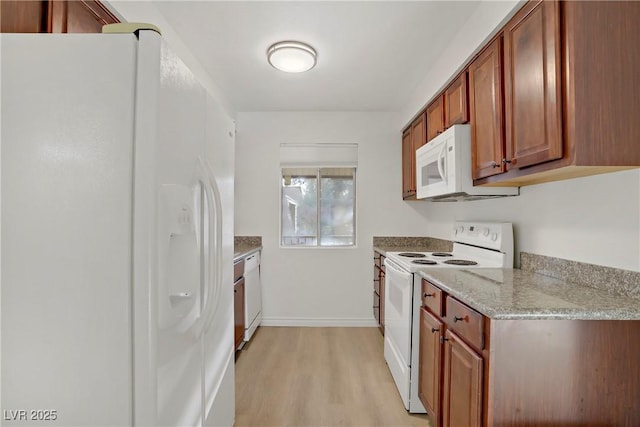 kitchen featuring brown cabinetry, light stone counters, baseboards, light wood finished floors, and white appliances