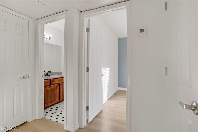 hallway featuring a sink and light wood finished floors