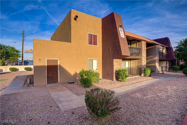 view of side of property featuring stucco siding and stone siding