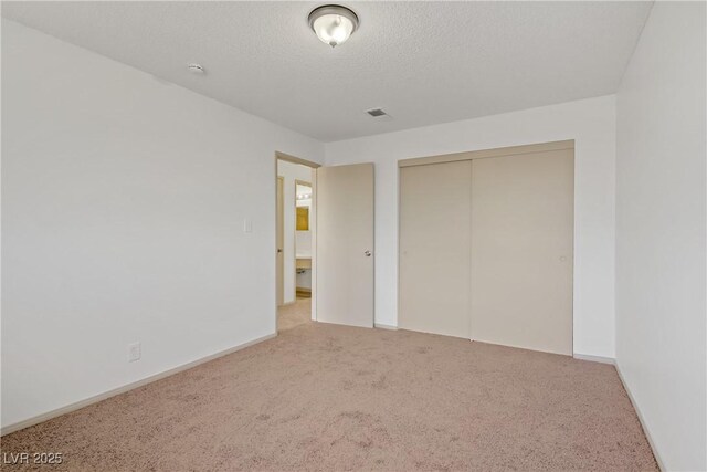unfurnished bedroom with a closet, carpet flooring, a textured ceiling, and visible vents
