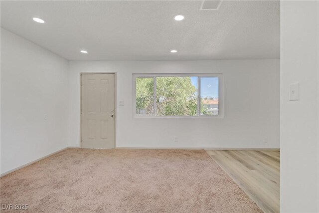 carpeted spare room with recessed lighting, baseboards, and visible vents