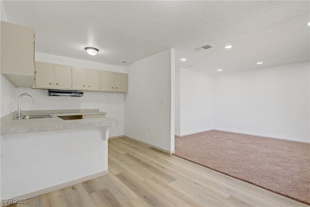 kitchen featuring light wood-type flooring, light countertops, a sink, and cream cabinetry