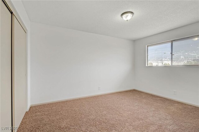 carpeted empty room with baseboards and a textured ceiling
