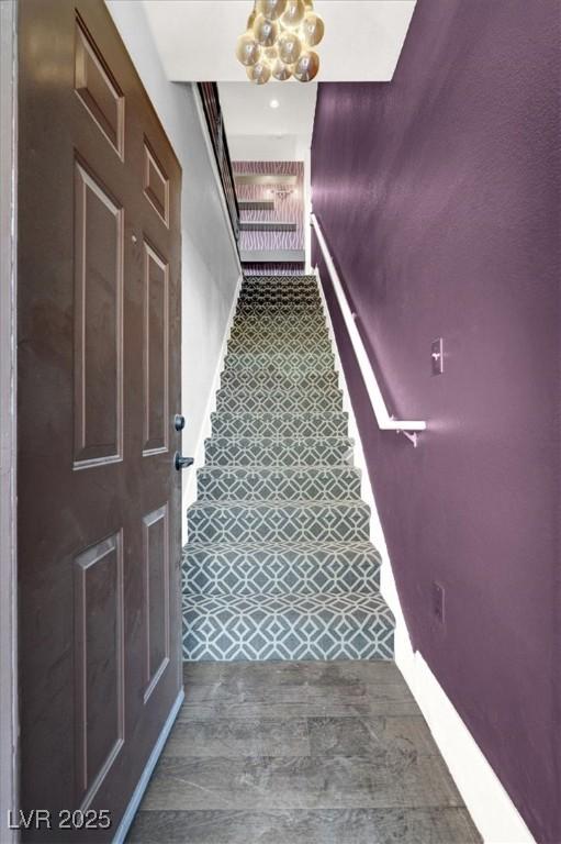 stairs featuring baseboards and a chandelier