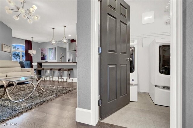 clothes washing area featuring baseboards, laundry area, wood finished floors, and a notable chandelier