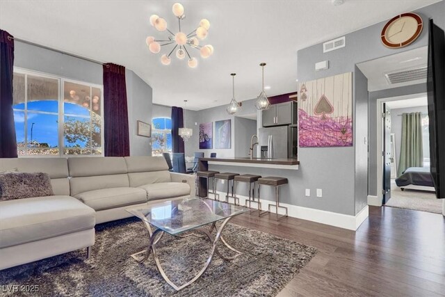 living area featuring visible vents, baseboards, wood finished floors, and a chandelier
