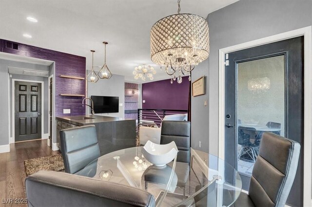 dining space featuring baseboards, visible vents, wood finished floors, and a notable chandelier
