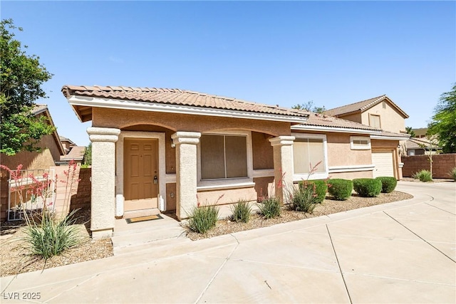 view of front of house featuring fence, an attached garage, a tile roof, stucco siding, and concrete driveway