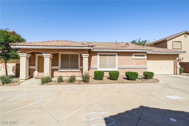 view of front of home with concrete driveway, a tiled roof, a garage, and stucco siding