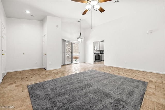 unfurnished living room with baseboards, ceiling fan, a high ceiling, and visible vents