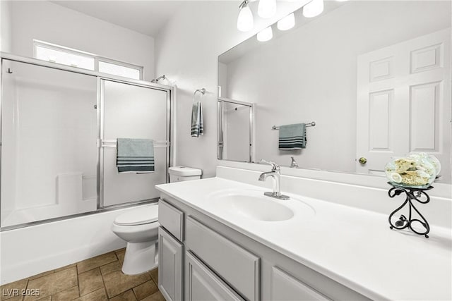 bathroom featuring vanity, combined bath / shower with glass door, and toilet