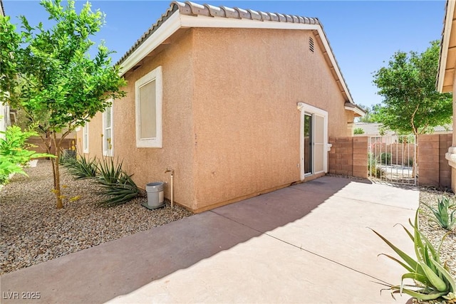 view of side of property featuring fence, a patio area, and stucco siding