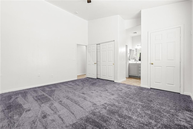 unfurnished bedroom with baseboards, a ceiling fan, carpet, and ensuite bath