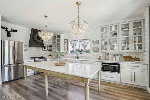 7566 Hope Valley St, Las Vegas, NV 89139 - kitchen with decorative backsplash, light stone countertops, custom range hood, appliances with stainless steel finishes, and a notable chandelier