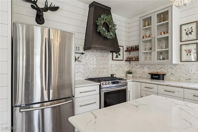 7566 Hope Valley St, Las Vegas, NV 89139 - kitchen with decorative backsplash, appliances with stainless steel finishes, custom exhaust hood, and glass insert cabinets