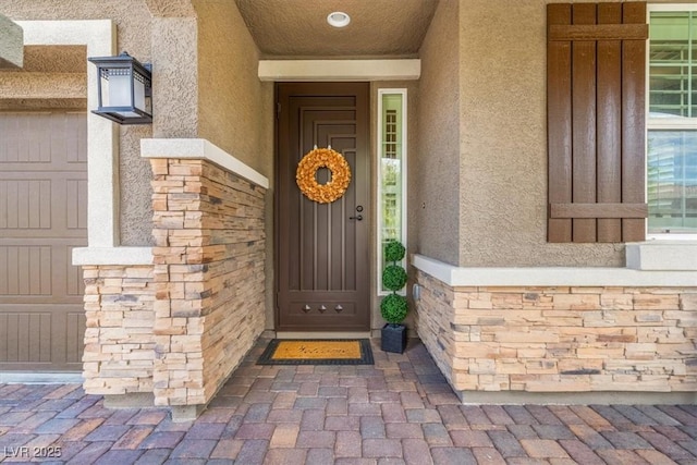 view of exterior entry with stone siding and stucco siding